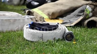 消防水管躺在草地上，手套和夹克的特写